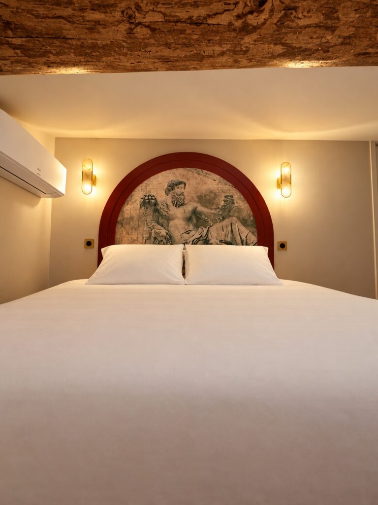 Chambre 1 de La Suite Romaine : lit double sous la fresque de Neptune