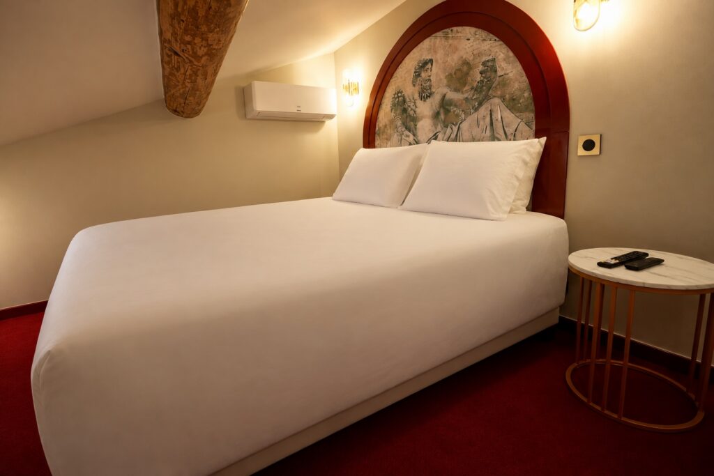 Chambre 1 de La Suite Romaine sous les poutres, lit double et table de chevet en marbre