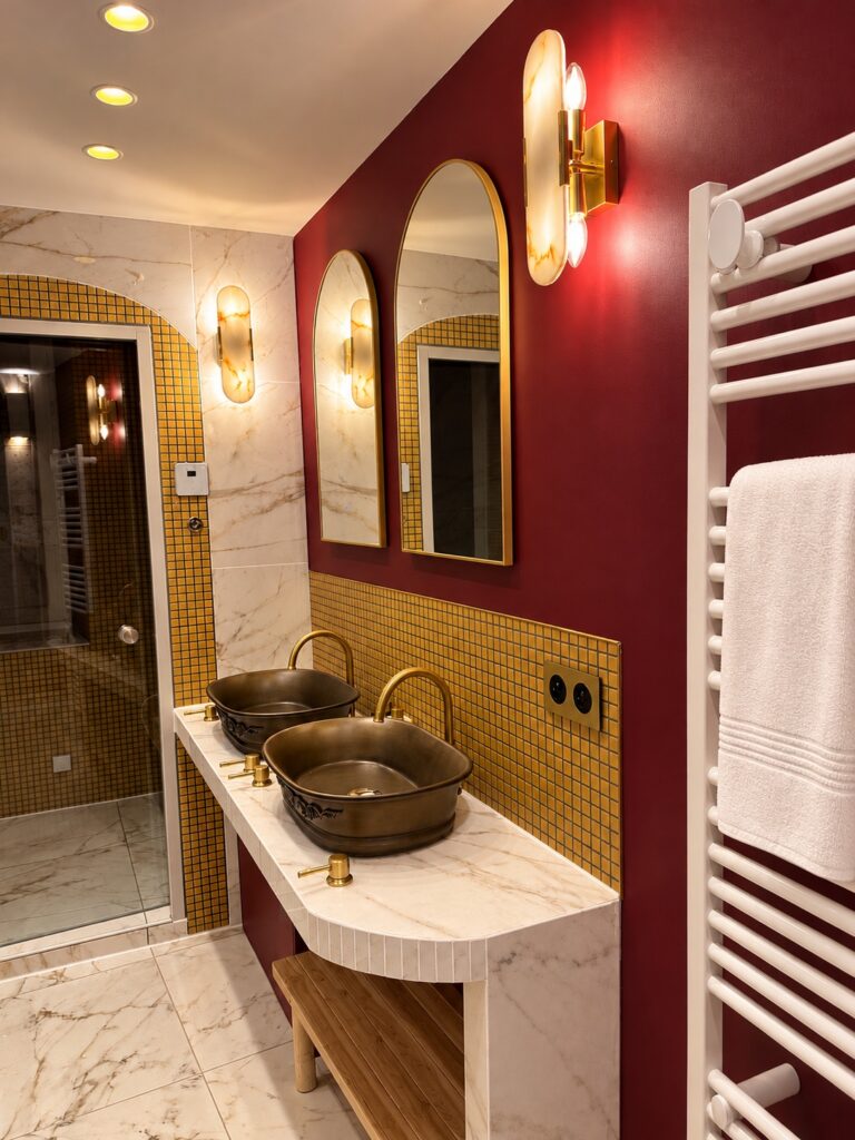 Salle de bain de La Suite Romaine : double vasque en bronze, miroirs dorés et douche