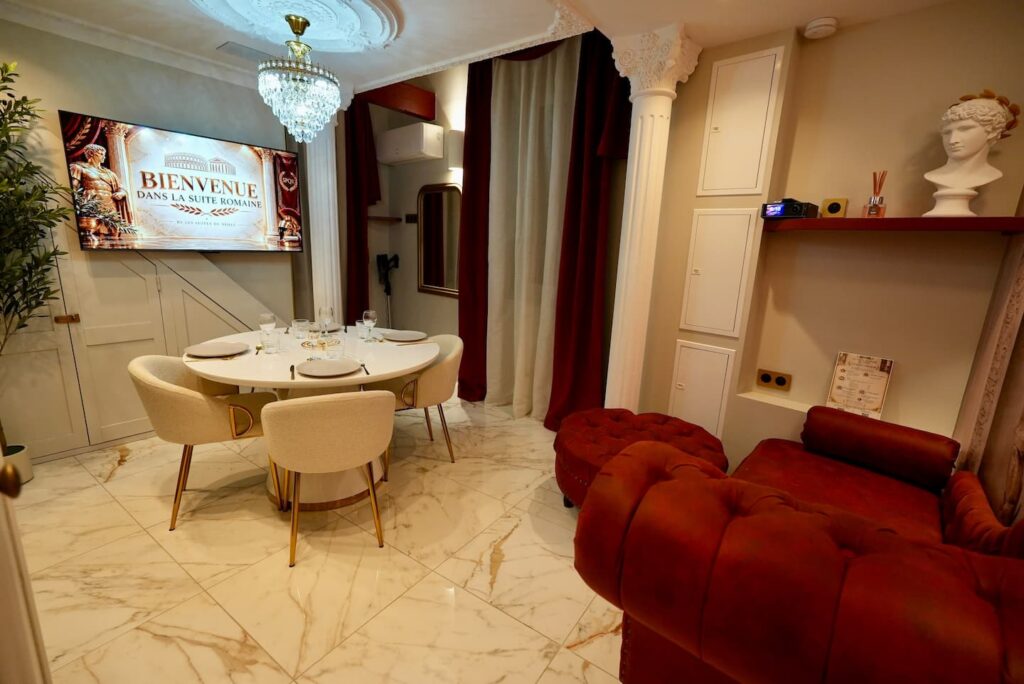 La Suite Romaine à Nîmes : salon et espace repas sous le lustre, colonnes romaines