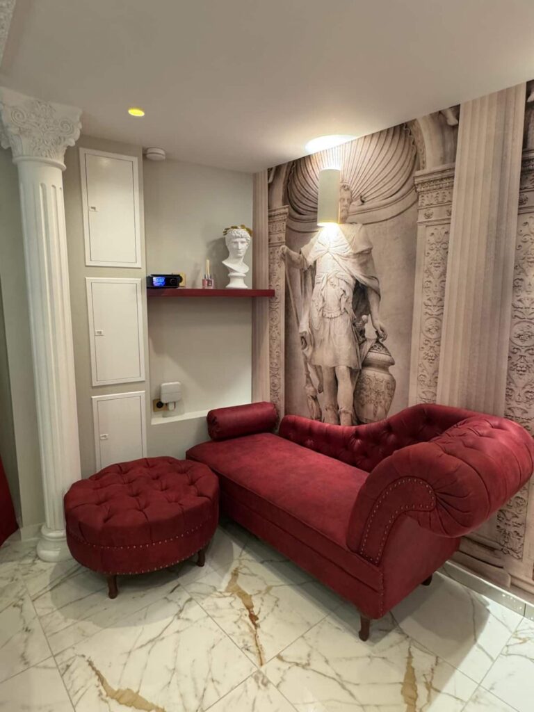 La Suite Romaine à Nîmes : salon de style romain, canapé rouge et statue